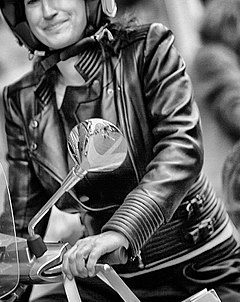 Woman in leather jacket on Vespa